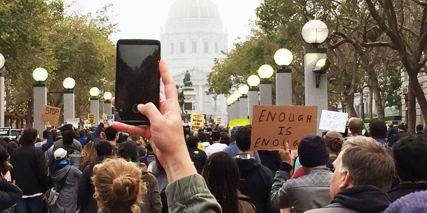 Hand holding iPhone at a protest
