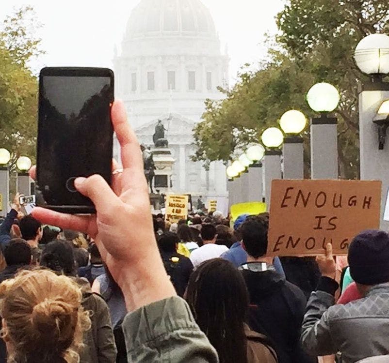 Hand holding iPhone at a protest